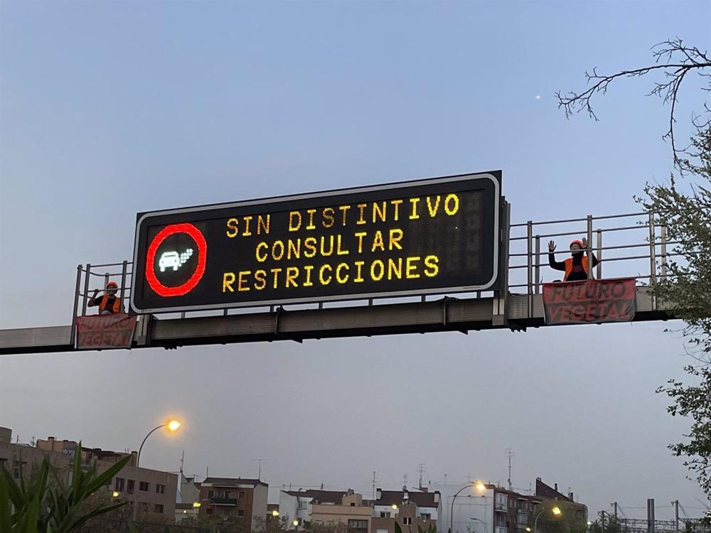 Dos activistas de Futuro Vegetal junto al cartel luminoso de la M-30. Dos
