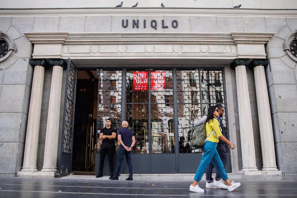 Archivo - Dos personas pasan por delante de la entrada de una tienda Uniqlo en la Gran Vía, la segunda que abre en Madrid, a 5 de octubre de 2022, en Madrid (España). Archivo