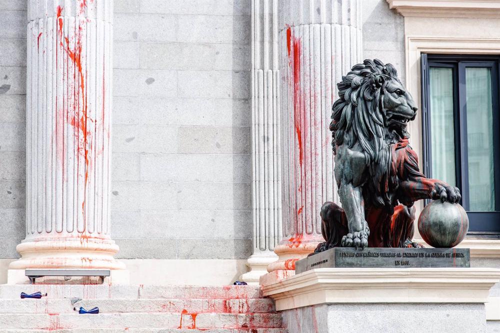 Uno de los leones del Congreso de los Diputados y las columnas teñidas con pintura roja por activistas de Futuro Vegetal y Rebelión Científica, a 30 de marzo de 2023, en Madrid (España). Los activistas han echado pintura roja sobre las escalinatas, column Uno
