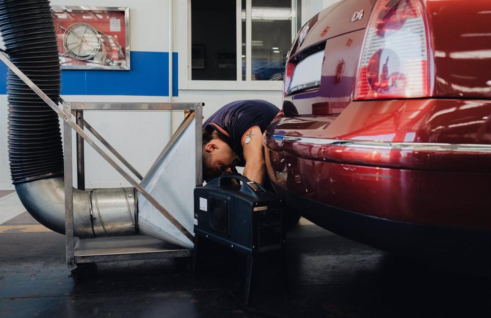 Archivo - Un trabajador realizando la ITV a un vehículo. Archivo