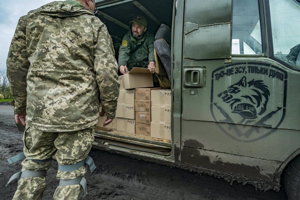 Un voluntario reparte suministros a un militar ucraniano en Donetsk. Un