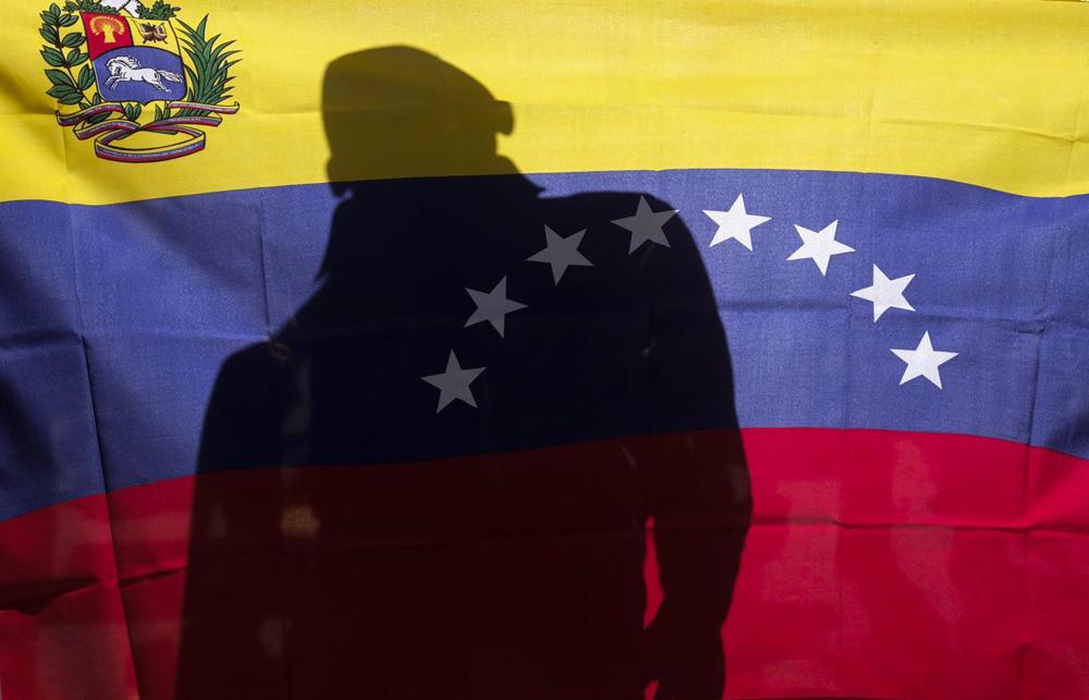 Archivo - Un hombre detrás de una bandera de Venezuela. Archivo