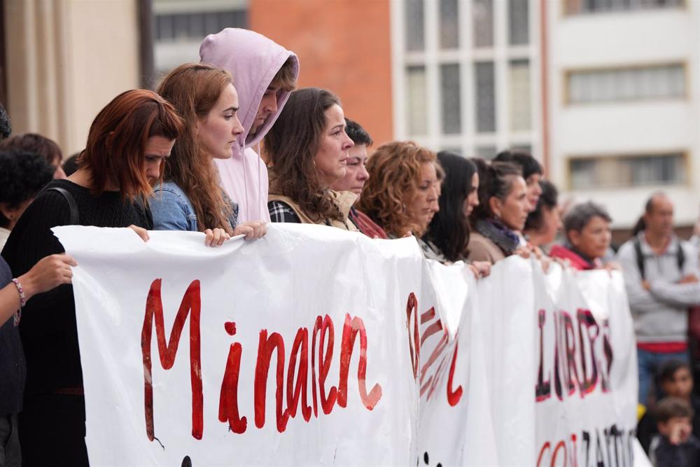 La pancarta de protesta por el crimen machista de una mujer en Orio, tras la que se han colocado sus dos hijos La
