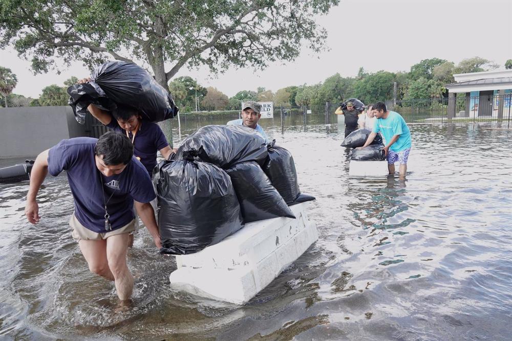 Archivo - 13 April 2023, US, Fort Lauderdale: People try and save valuables, wading through flood waters in the Edgewood neighbourhood of Fort Lauderdale, Florida. South Florida was drenched by rain Wednesday, causing major flooding. Photo: Joe Cavaretta/ Archivo