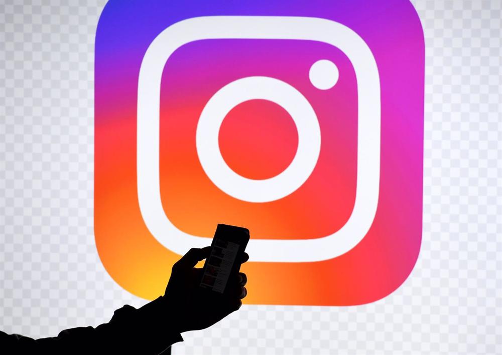 Archivo - FILED - 15 March 2019, Schleswig-Holstein, Aukrug-Homfeld: A man holds a smartphone in front of a monitor with the logo of Instagram. Photo: Carsten Rehder/dpa Archivo
