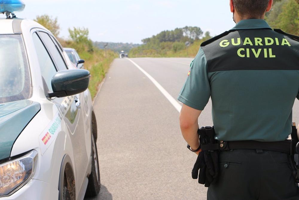 Archivo - Un agente de la Guardia Civil junto a un coche. Archivo