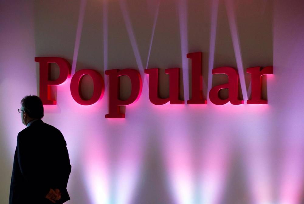 Archivo - FILE PHOTO: A man stands next to the logo of Spain's Banco Popular during the bank's results presentation in Madrid Archivo